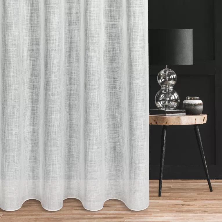 Firana szyta na taśmie fala biała o luźnym splocie z dodatkiem transparentnej nici, nadającej delikatny połysk tkaninie, wykończona obciążnikiem