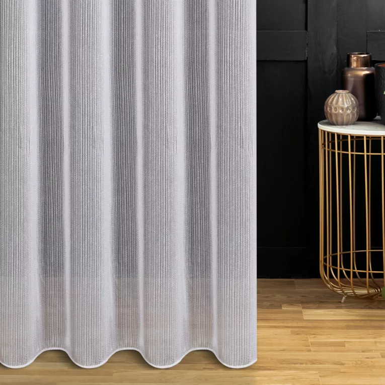 Firana szyta na tunelu jasnoszara z drobnej siatki w pionowe prążki, wykończona obciążnikiem