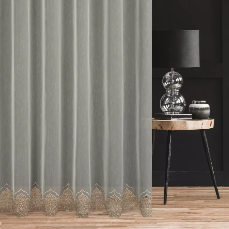 Firana szyta na tunelu kremowo złota z matowej tkaniny zdobionej dołem delikatną aplikacją z dodatkiem połyskującej nici Pierre Cardin