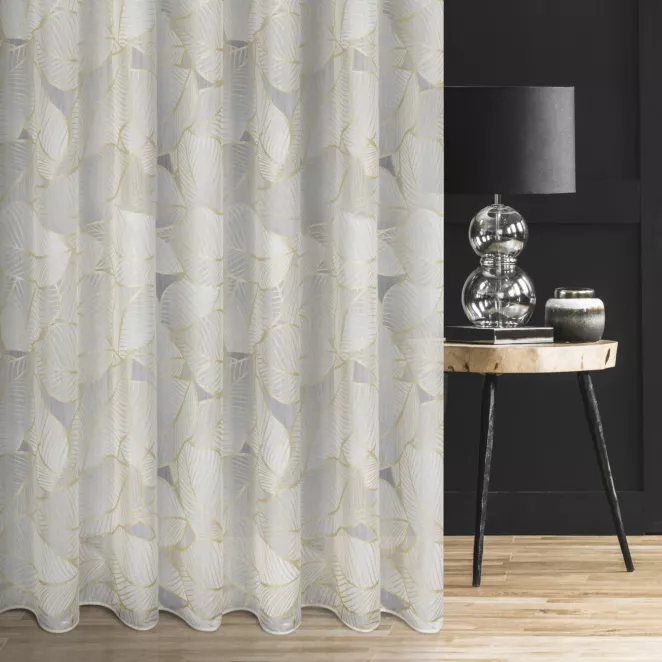 Firana szyta na przelotkach biało złota z tkaniny typu BATYST z delikatnie połyskującym nadrukiem w kształcie liści po całości tkaniny, wykończona obciążnikiem