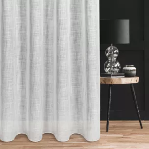 Firana szyta na taśmie fala biała o luźnym splocie z dodatkiem transparentnej nici, nadającej delikatny połysk tkaninie, wykończona obciążnikiem