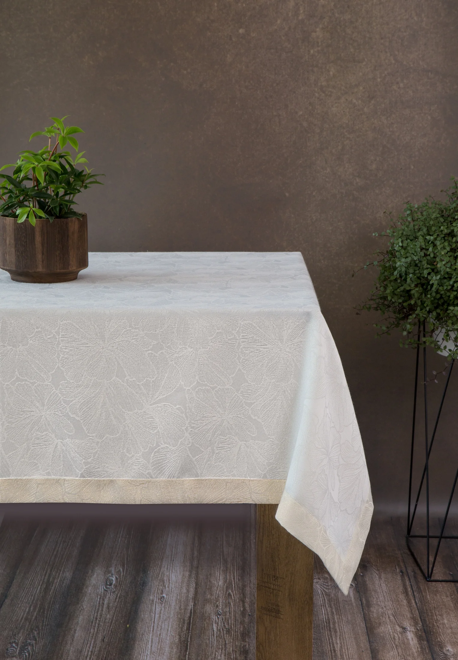 Obrus kremowy 145x400 cm LILIAN z delikatnym wzorem liści z tkaniny przeplatanej złotą nicią z elegancką podwójną listwą